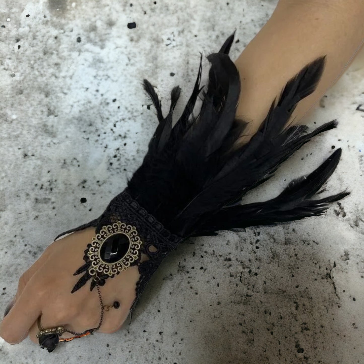 Zwart kanten polsstuk met groot amulet met zwarte steen, aanpasbare ring en zwarte veren