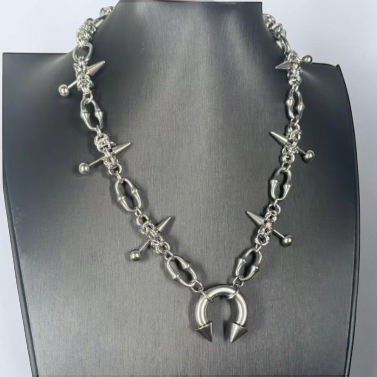 Halsketting met groffe halve cirkel en pinnen met bolletjes en studs
